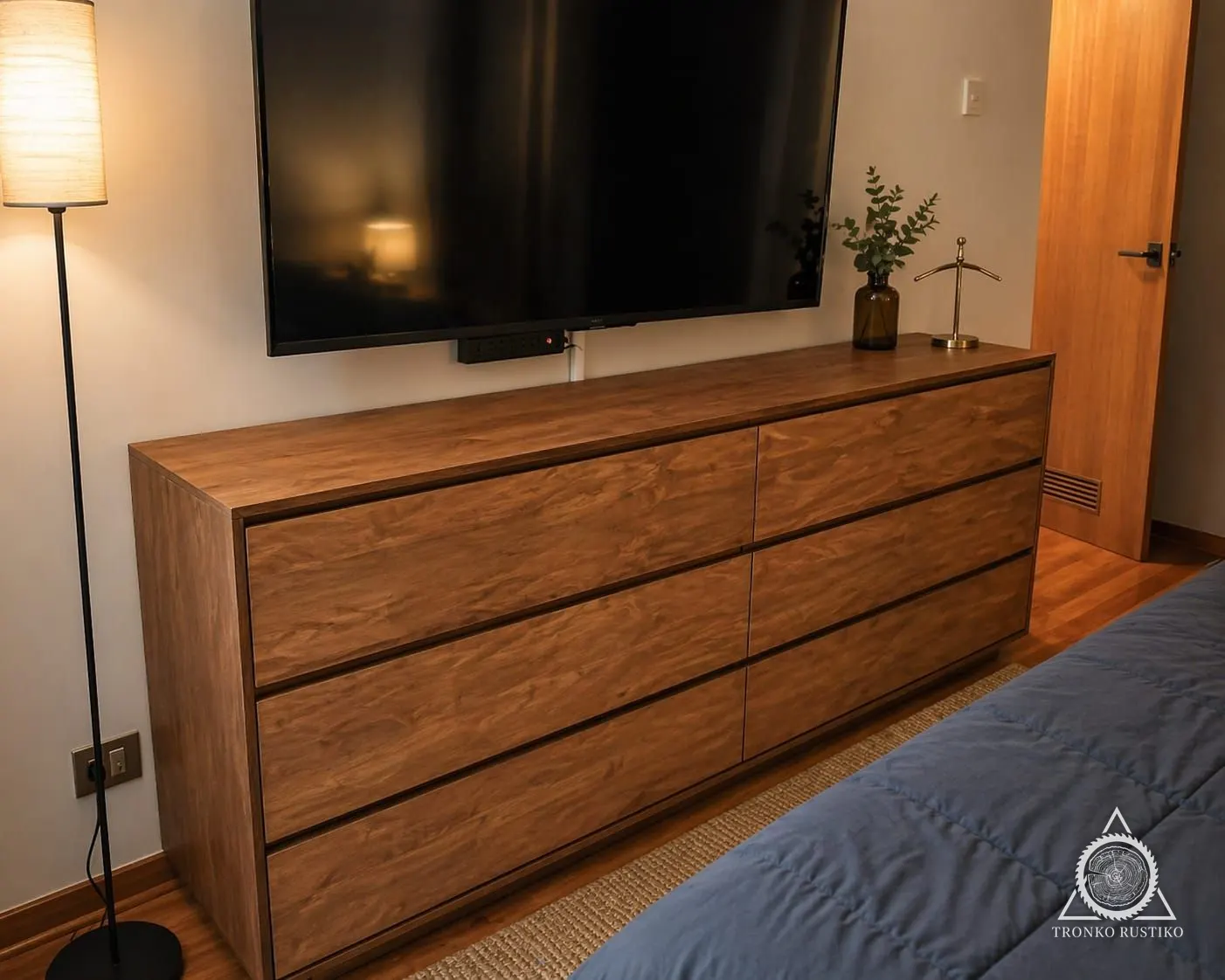 Cómoda baja y larga de madera con seis cajones sin tiradores visibles, bajo un televisor.
