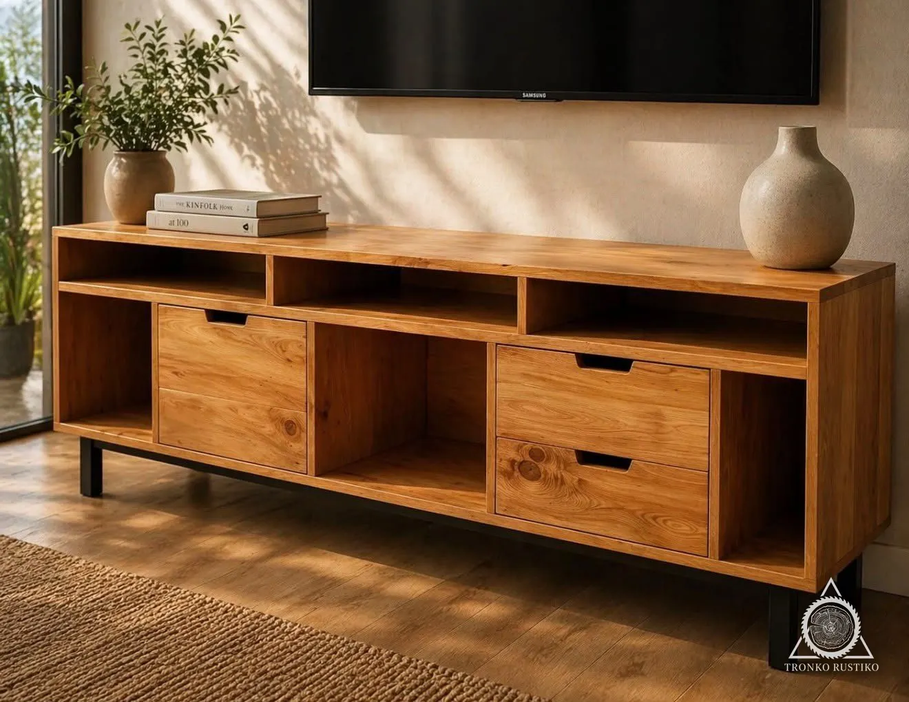 Rack de madera clara con nichos abiertos arriba, cajones con tiradores rebajados abajo y patas metálicas negras, bajo un televisor.