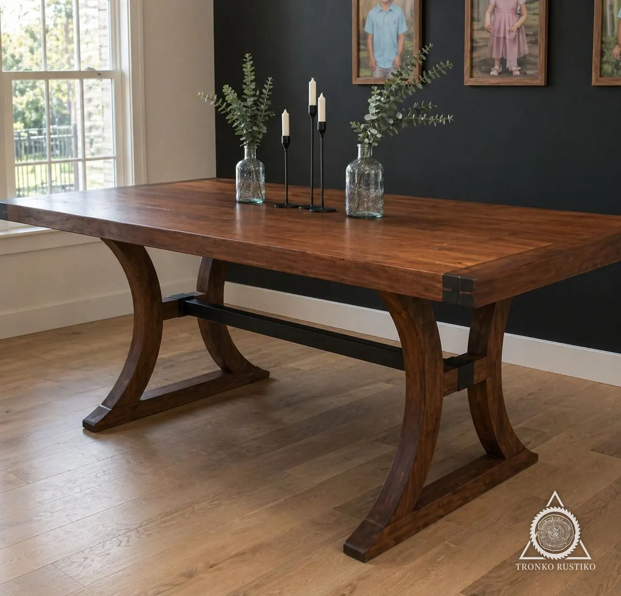 Mesa de comedor de madera oscura con bases curvas y un travesaño de fierro negro.