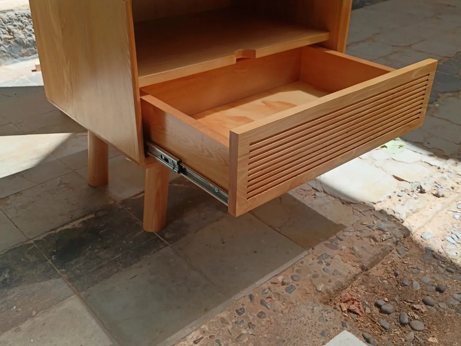Cajón de velador abierto, con la corredera metálica a la vista.