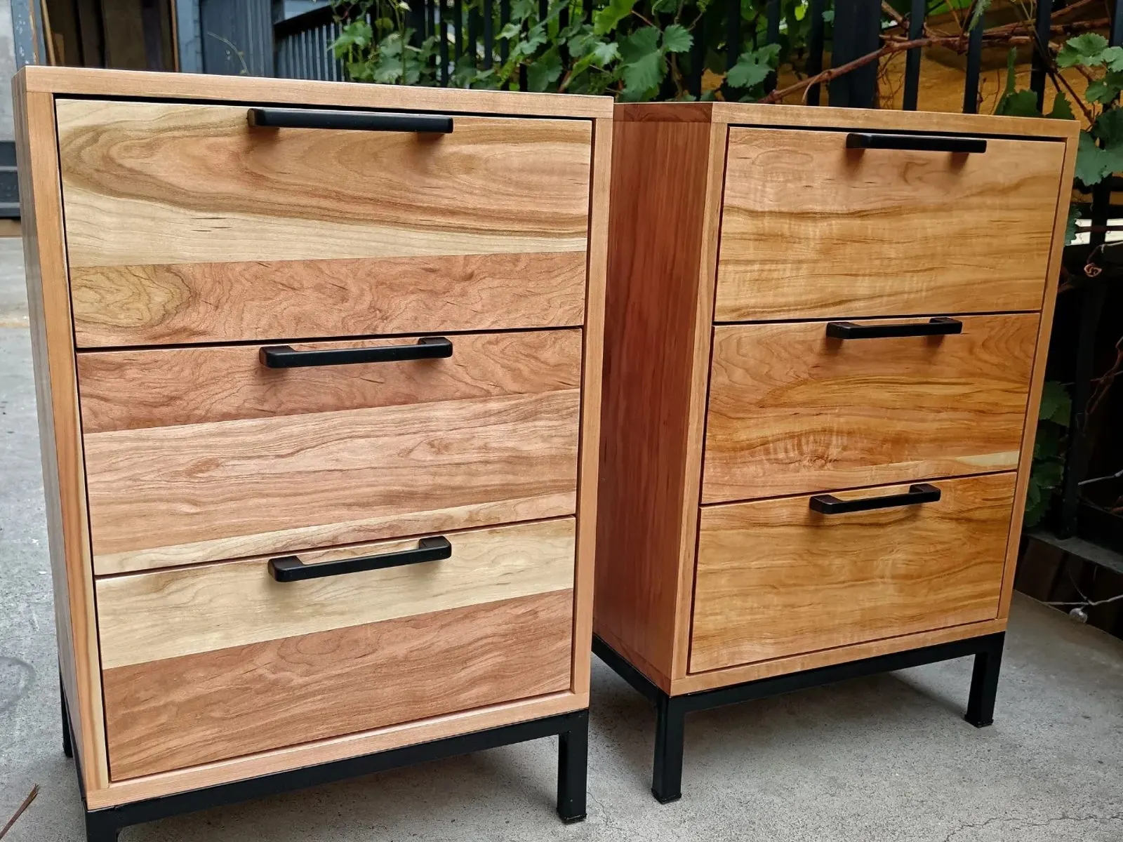 Par de veladores de madera con base de acero negro, en el taller.