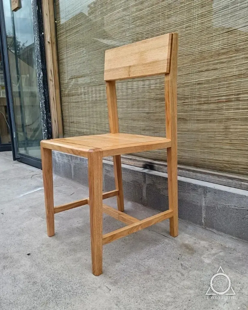 Silla de madera clara de líneas rectas con respaldo de tabla.