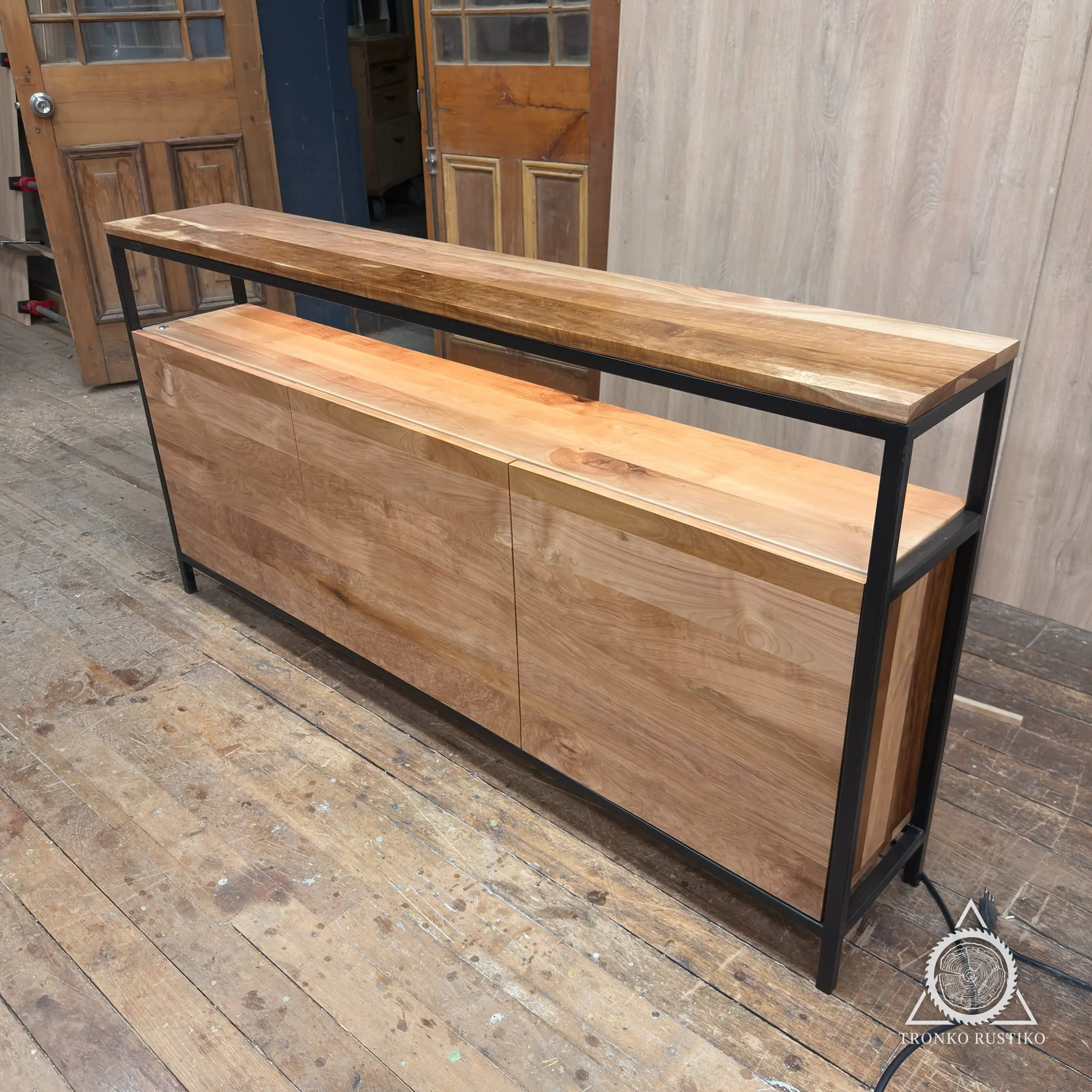 Rack de madera clara con tres puertas, estructura de acero negro y cubierta superior, recién terminado en el taller.
