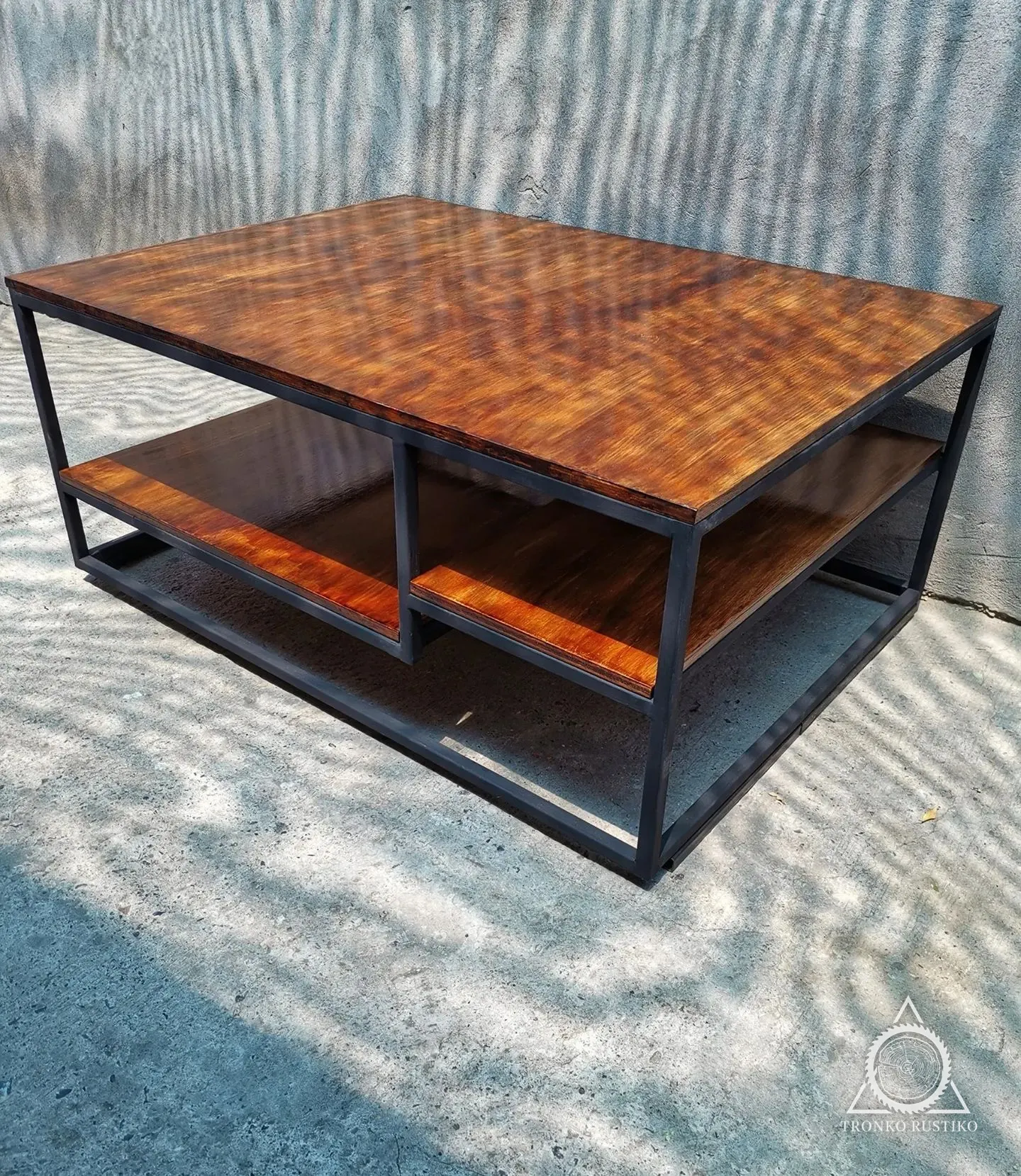 Mesa de centro de madera de veta marcada con estructura metálica negra y repisa inferior.