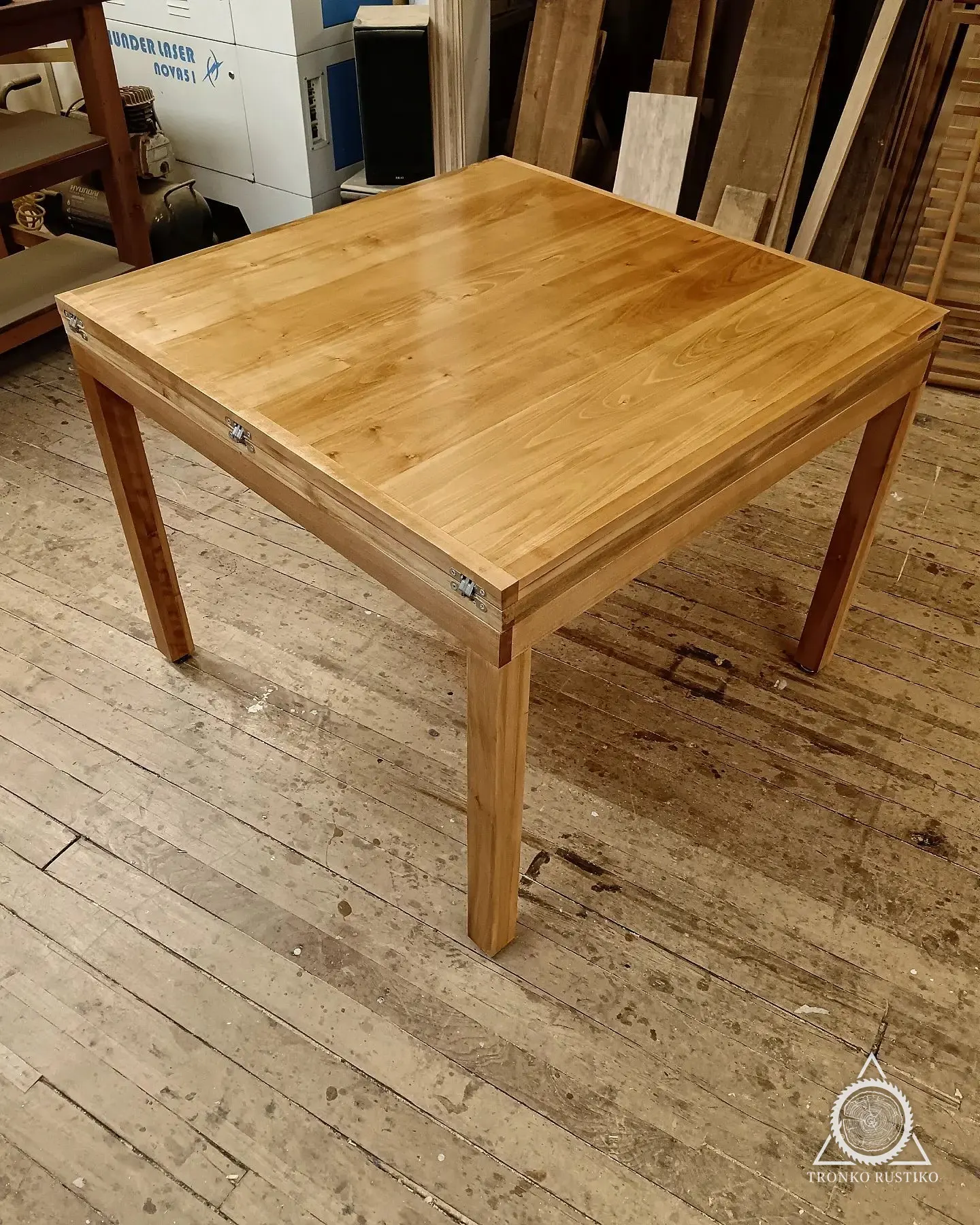 Mesa de comedor cuadrada de madera clara con patas rectas.
