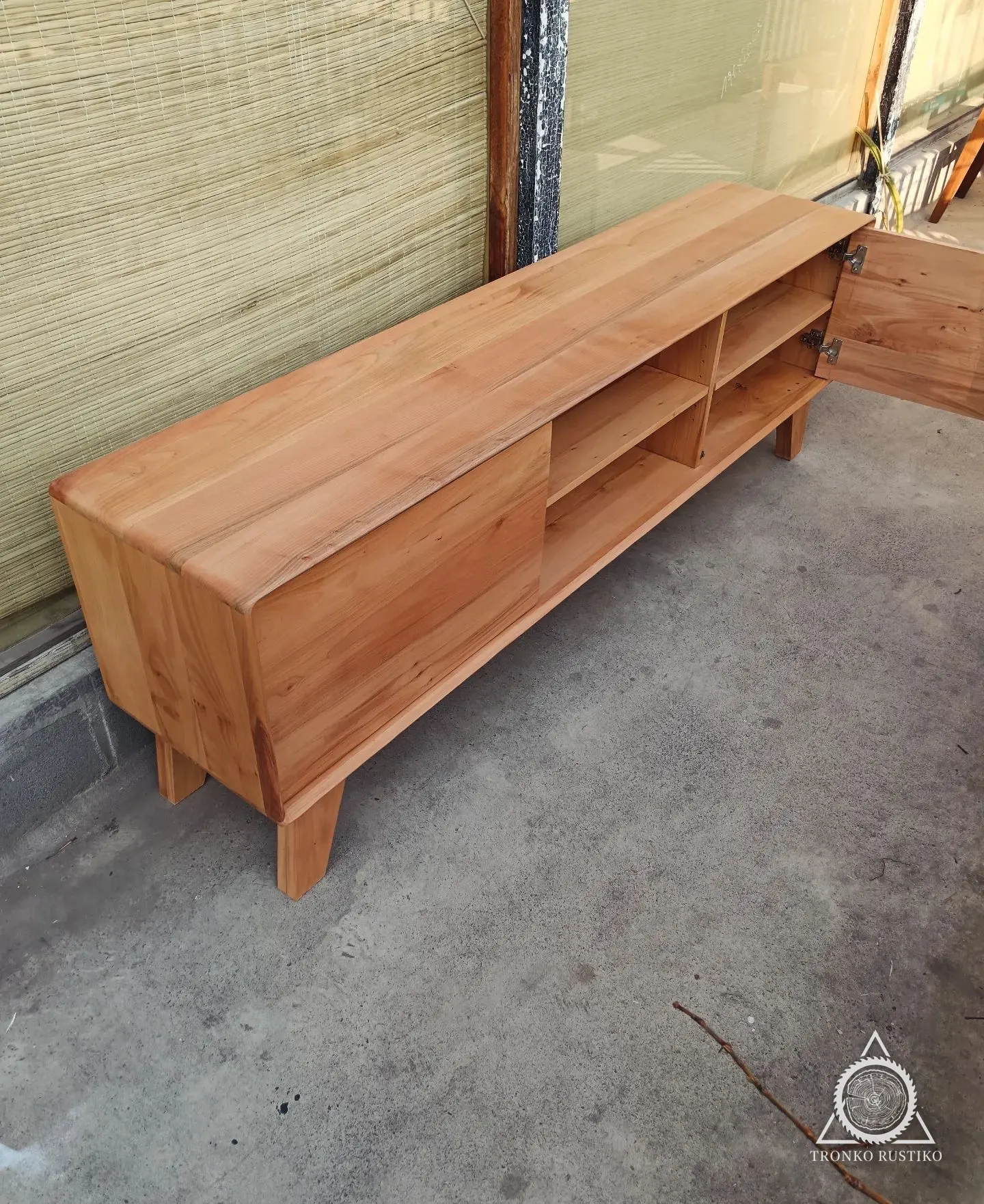 Rack de madera clara con puertas laterales, nichos centrales y patas inclinadas.