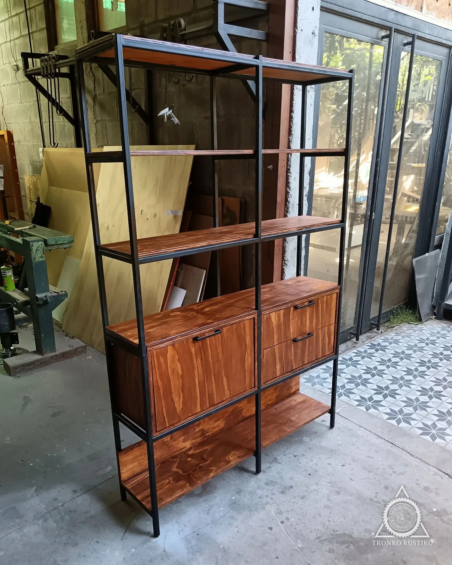 Librero de estructura metálica negra con repisas de madera y un módulo cerrado.